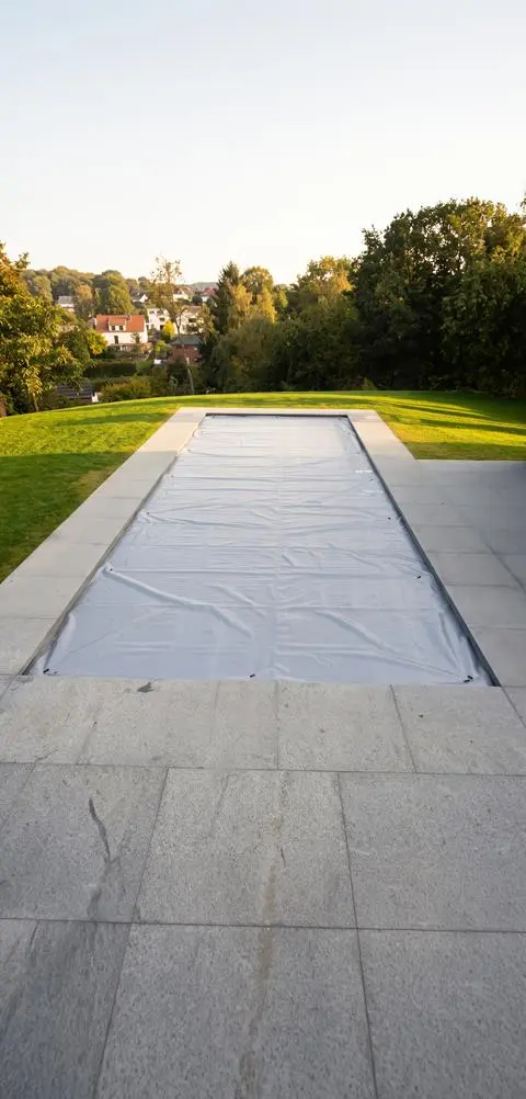 Piscine couverte d’une bâche d’hivernage grise